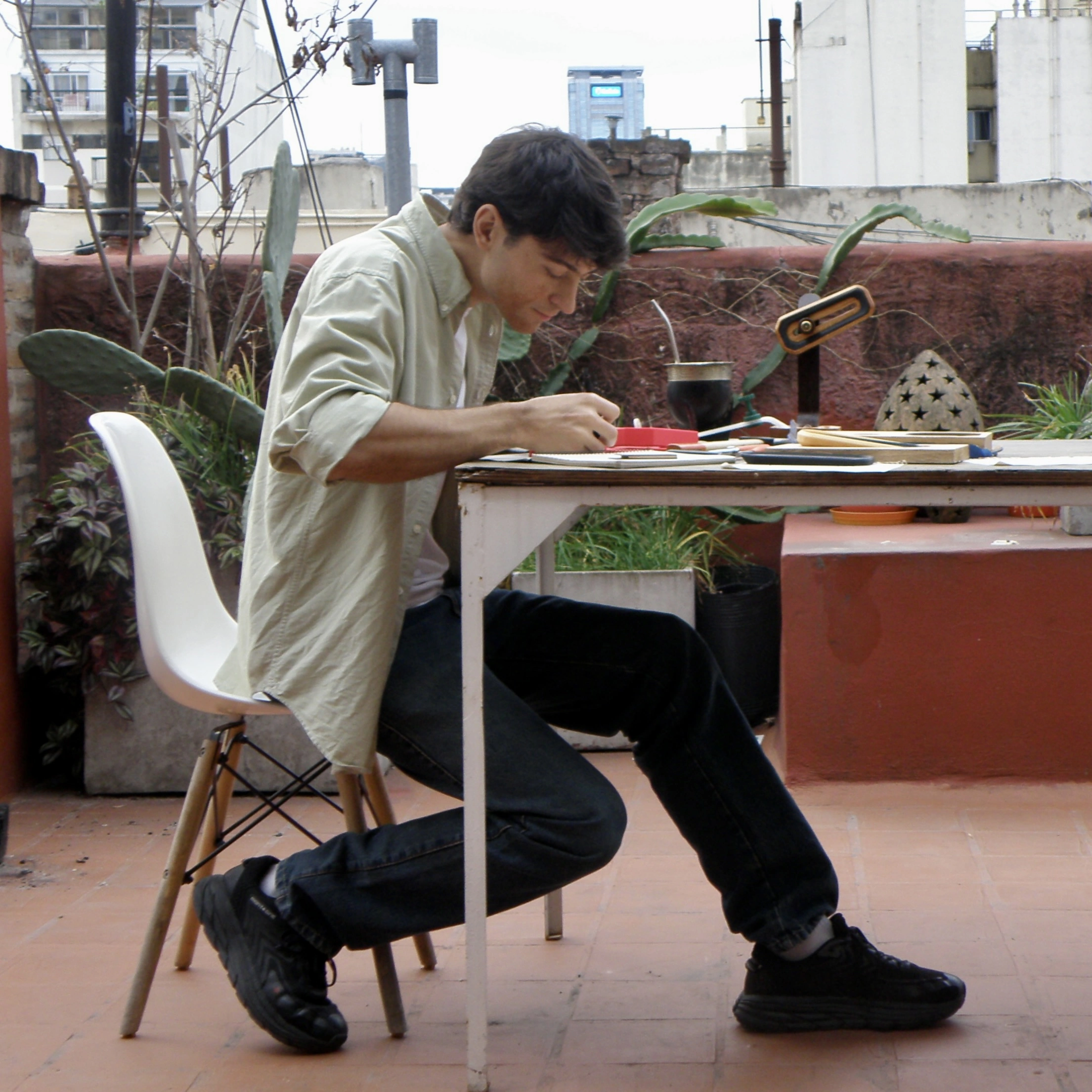 Jesus Elisaleco trabajando en su mesa de la terraza, rodeado de prototipos